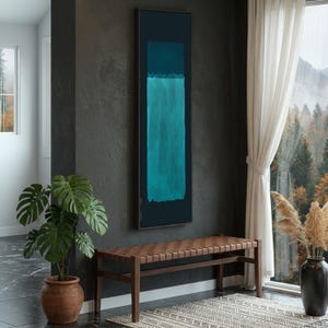 Puede incluir: Pintura abstracta enmarcada con fondo azul oscuro y dos formas rectangulares en tonos turquesa y verde azulado. Cuelga sobre un banco de cuero marrón en una habitación con una gran ventana.