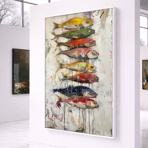 May include: A vertical framed painting featuring a stack of eight stylized fish in various colors including yellow, green, red, and blue. The artwork uses thick, textured brushstrokes with visible paint drips against a neutral, off-white background.