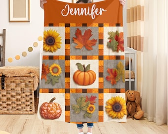 Könnte beinhalten: Eine orangefarbene und braune Herbstdecke mit einem Patchwork-Design. Die Decke zeigt Sonnenblumen, Kürbisse und Herbstblätter. Der Name "Jennifer" ist in weißer Schrift oben aufgedruckt.