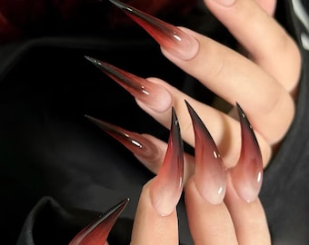 May include: Long, sharp, stiletto nails with a black to red ombre gradient. The nails are clear and have a glossy finish.