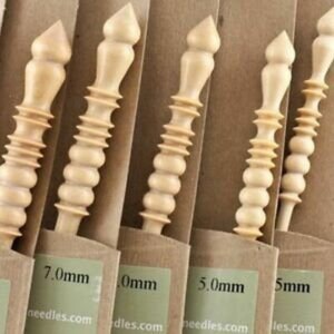 May include: Set of four wooden knitting needles with a unique, beaded design. The needles are labeled with their sizes: 7.0mm, 6.0mm, 5.0mm, and 5mm. needles.com