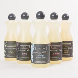 Puede incluir: Cinco botellas de concentrado de lavandería delicada Eucalan, cada una con un aroma diferente. Las botellas son transparentes con etiquetas negras y tapas de color gris oscuro. Los aromas incluyen eucalipto, lavanda, sin perfume, pomelo y jazmín. Cada botella contiene 500 ml.