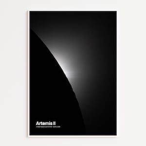 May include: A black and white print featuring a celestial scene. The image shows a dark, curved shape against a bright, glowing background. The text "Artemis II" is at the bottom, with additional text below.