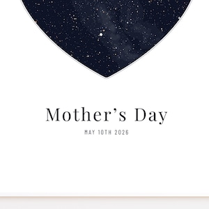 May include: A white print with a dark blue heart-shaped design filled with white specks, resembling stars. The words "Mother's Day" are printed in black, with "MAY 10TH 2026" below. The print is on a white background.
