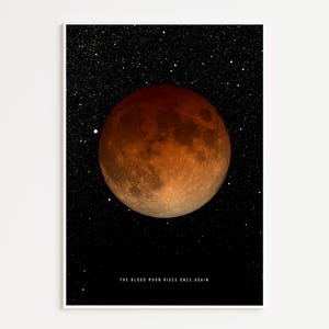Puede incluir: Impresión enmarcada que muestra una luna de sangre contra un cielo estrellado. La luna es de color naranja rojizo, con una superficie detallada. El texto "THE BLOOD MOON RISES ONCE AGAIN" está impreso en la parte inferior.