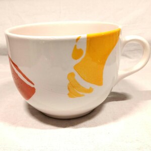 May include: A white ceramic mug with a large handle. The mug has a yellow and orange abstract design.