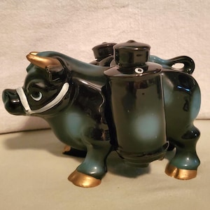 May include: Black and blue ceramic bull figurine with three salt and pepper shakers on its back. The shakers have black lids and white accents.