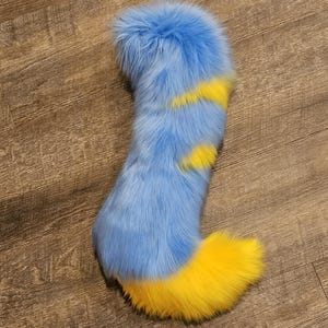 May include: A blue and yellow fluffy tail with a long, blue body and a yellow tip. The tail is made of soft, plush fur.