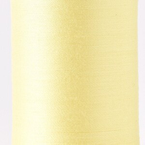 May include: A spool of pale yellow thread wound on a clear plastic bobbin.