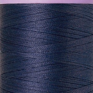 May include: A spool of dark blue Mettler Silk-Finish cotton mercerized thread, No. 50. The spool has a lavender-colored top and bottom with the brand name and thread details. Contains 547 yards of thread.