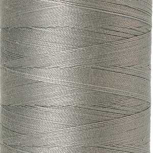 Może przedstawiać: Szpulka szarej nici bawełnianej merceryzowanej Mettler Silk-Finish. Szpulka jest oznaczona "No. 50" i "500m/547 yds".