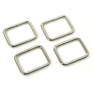 May include: Four silver metal D-rings, each with a square shape and a smooth, polished finish.