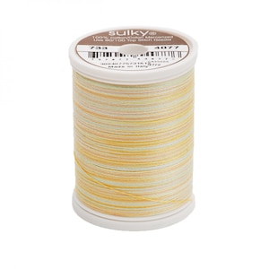 Könnte beinhalten: Eine Spule Sulky 100% Baumwolle mercerisiertes Garn in einem mehrfarbigen Muster aus Gelb, Orange und Grün. Die Spule ist mit den Nummern 733 und 4077 gekennzeichnet. Das Etikett lautet auch "Made in Italy".