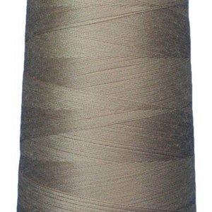 Puede incluir: Una bobina de hilo beige enrollada alrededor de una bobina de plástico blanca.