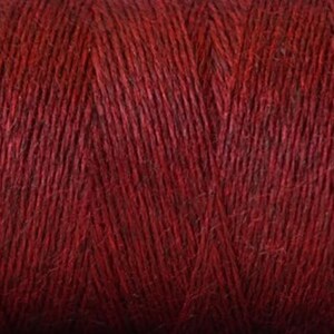 May include: Close-up of a spool of deep red yarn. The yarn is made of natural fibers and has a slightly textured surface.