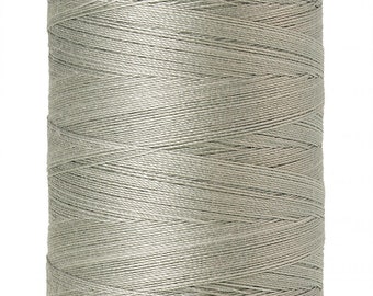 May include: A spool of Mettler Silk-Finish thread in a muted green color. The spool has a lavender-colored top and bottom with the brand name and thread details printed on it. The thread is wound tightly around the spool.