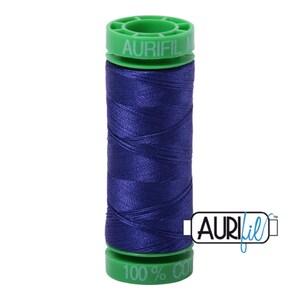 May include: A spool of dark blue thread with a green label that reads "Aurifil 100% Cotton" and "Aurifil" in a stylized font.