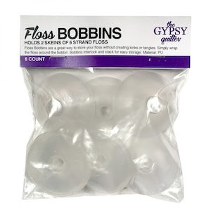 Może przedstawiać: Opakowanie sześciu przezroczystych plastikowych szpulek do nici, z etykietą "Floss Bobbins" i "The Gypsy Quilter". Opakowanie informuje, że szpulki mieszczą dwie kłębki nici sześciożyłowych i są wykonane z PU.