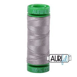 Puede incluir: Una bobina de hilo Aurifil gris, 100% algodón, con una bobina de plástico verde.