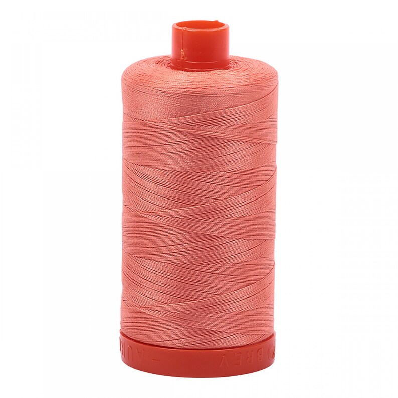 May include: A spool of coral-colored thread, tightly wound around a cylindrical core. The thread is a solid, uniform color, and the spool has a red top and base. Ideal for sewing, embroidery, or other textile crafts.