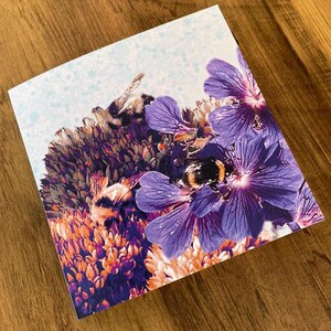 Un lavoro d'amore, biglietto d'auguri quadrato a due ante viola e blu (vuoto all'interno) con tre bombi al lavoro.