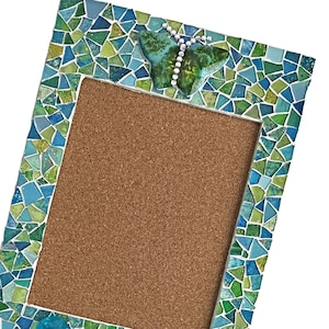 Quadro de cortiça com mosaico de borboletas, quadro de avisos azul-esverdeado com puxadores.