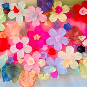 May include: Assortment of colorful plastic flowers and leaves in various shapes and sizes. The flowers are in shades of pink, purple, blue, red, and yellow. The leaves are green and brown.