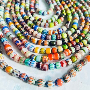 May include: A close-up of a collection of colorful glass beads with intricate patterns. The beads are arranged in a circular pattern, creating a visually appealing display.