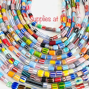 May include: A collection of colorful glass beads, featuring various patterns and designs. The beads are arranged in a circular pattern, creating a visually appealing display. The beads are perfect for jewelry making, crafting, and home decor.