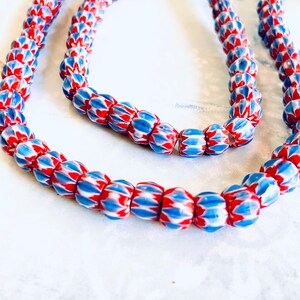 May include: A strand of red, white, and blue glass beads. The beads have a unique, textured design.