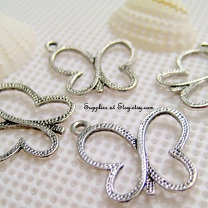 May include: Four silver metal butterfly charms with a textured surface. The charms have a loop at the top for attaching to jewellery or other crafts.