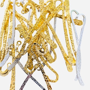 May include: A pile of gold and silver bookmark with intricate designs. The bookmarks are made of metal and have a decorative, ornate look.