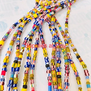 May include: A collection of colourful beaded necklaces with yellow, blue, red, white and black beads. The beads are arranged in a variety of patterns, including stripes and polka dots.