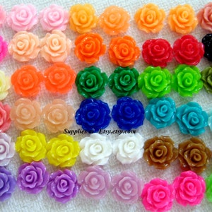May include: Assortment of 36 colourful resin rose cabochons, each measuring approximately 1 inch in diameter. The roses are in various colours, including pink, red, orange, yellow, green, blue, purple, and white.