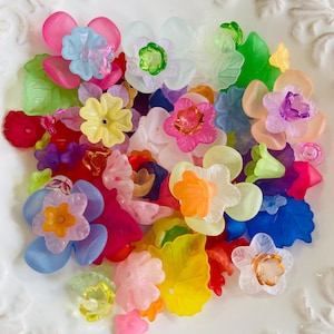 Pode incluir: Conjunto de contas de plástico em forma de flor coloridas em vários tons de rosa, azul, amarelo, laranja, verde e roxo. As contas são translúcidas e têm um acabamento brilhante.