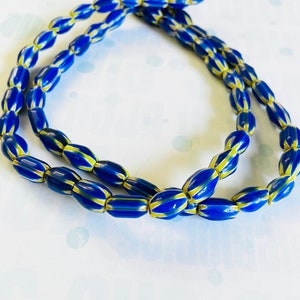 May include: A strand of blue and yellow glass beads. The beads are oval shaped and have a striped pattern.