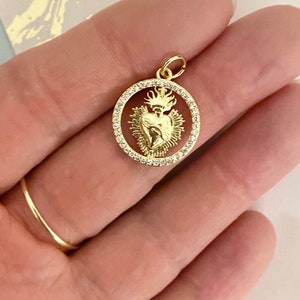 Peut inclure: Pendentif dor&eacute; repr&eacute;sentant une image d&eacute;taill&eacute;e d'un c&oelig;ur avec une couronne et des flammes, entour&eacute; d'un cercle de pierres brillantes transparentes.
