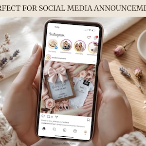 May include: A smartphone displays an Instagram post announcing a baby girl. The post includes a framed announcement with a pink bow, a onesie, and the text "Baby Girl is on the way, coming August 2025." The phone is held by a person.