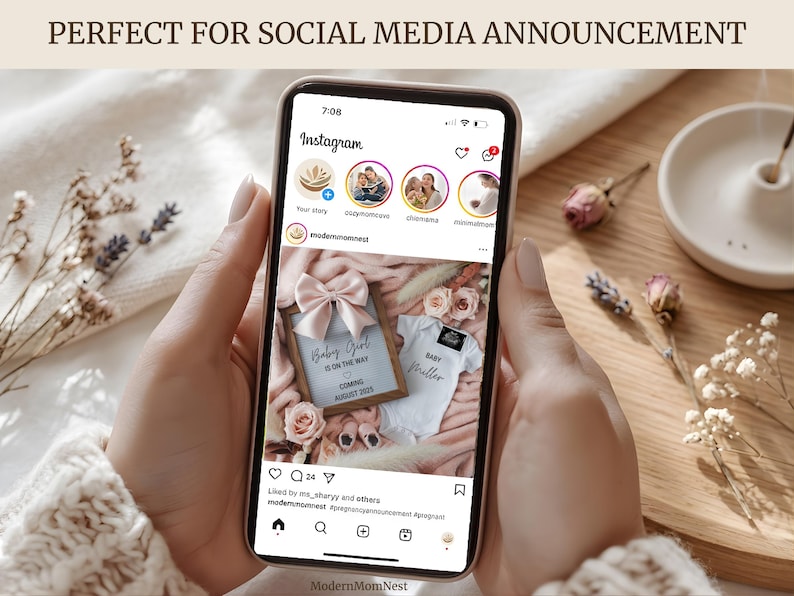 May include: A smartphone displays an Instagram post announcing a baby girl. The post includes a framed announcement with a pink bow, a onesie, and the text "Baby Girl is on the way, coming August 2025." The phone is held by a person.