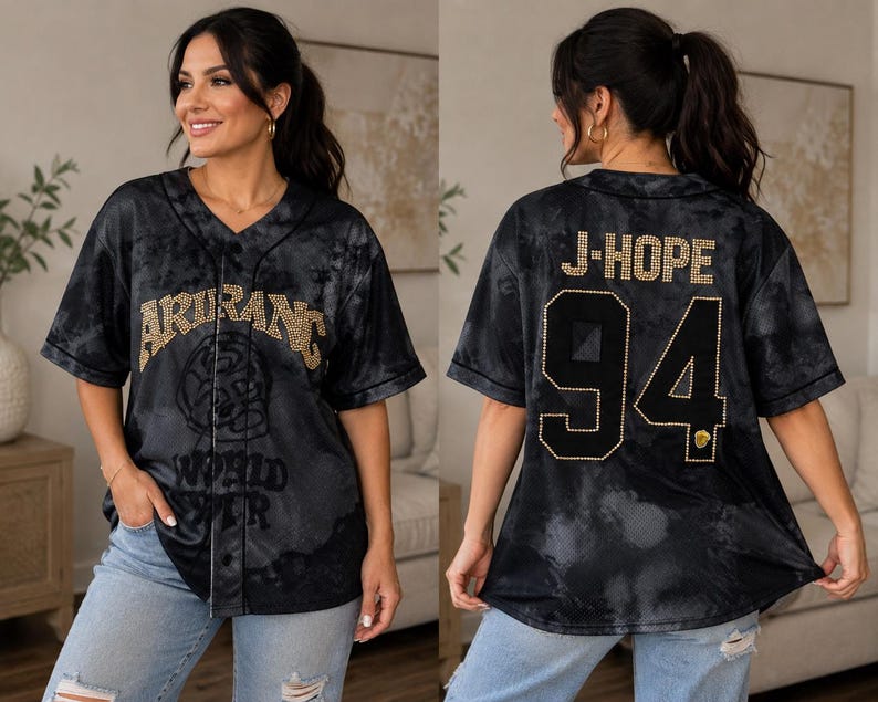 Pu&ograve; includere: Una maglia da baseball nera e grigia con effetto tie-dye, scollo a V e chiusura frontale con bottoni. La parte anteriore presenta la scritta ARIRANG WORLD TOUR in strass dorati. Il retro mostra la scritta J-HOPE e il numero 94 in strass dorati.