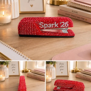Pu&ograve; includere: Una cucitrice rossa interamente ricoperta di piccoli strass rossi scintillanti. Il lato della cucitrice presenta la scritta "Spark 26" formata da cristalli chiari e riflettenti sullo sfondo di strass rossi, con un meccanismo in metallo argentato.