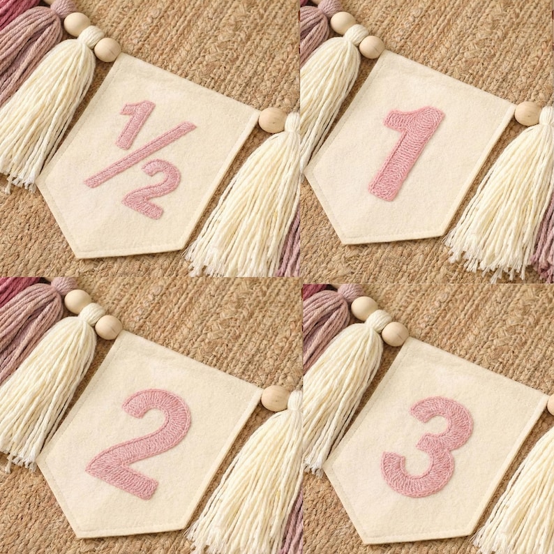 K&ouml;nnte beinhalten: Ein Banner mit vier cremefarbenen Wimpeln, die jeweils eine rosa Zahl oder einen Bruchteil zeigen: 1/2, 1, 2 und 3. Die Wimpel sind mit cremefarbenen Quasten und Holzperlen verziert, was einen festlichen Look erzeugt.