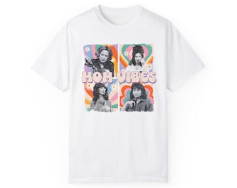 May include: White t-shirt with a colorful graphic print of four women and the text "MOM VIBES" in a retro font.