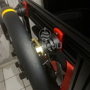 Peut inclure: Un châssis de cockpit de simulateur de course noir avec un volant noir, des supports rouges et une ceinture de sécurité rouge. Le volant a des accents jaunes. Le cockpit est monté sur un sol carrelé.