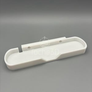 Peut inclure: Support mural en plastique blanc avec un dessus incurvé et une fente au milieu. Le support a deux petits trous sur le dessus et un sur le côté. Le texte "Roche3D" est visible sur le support.