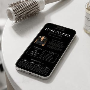 以下が含まれることがあります： ヘアスタジオの黒いウェブサイトインターフェースを表示したスマートフォン。HAIR STUDIO、BUSINESS HOURS、BOOKING POLICIESなどの見出し、円形のポートレート、連絡先情報、予約やキャンセルに関するアイコンが表示されています。
