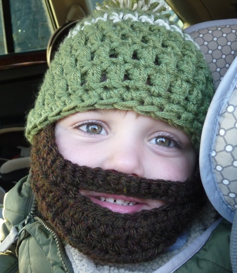 Puede incluir: Un ni&ntilde;o con un gorro de punto verde con un pomp&oacute;n blanco y una barba de punto marr&oacute;n.