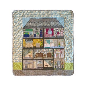 May include: A handmade quilt with a dollhouse design. The quilt depicts various rooms with furniture and decor, including bedrooms, a living room, and a kitchen. The quilt has a light blue patterned border and a green and brown trim.