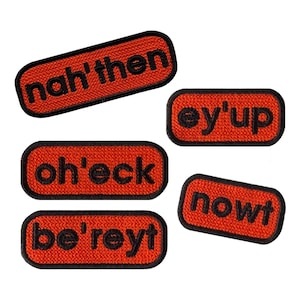 May include: Five rectangular embroidered patches with rounded corners, featuring a vibrant orange background and a thick black border. Each patch displays black text reading nah'then, ey'up, oh'eck, be'reyt, and nowt in a bold, sans-serif font.