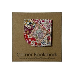 May include: A pink and red patchwork fabric corner bookmark with a silver glitter trim. The bookmark is on a brown card with the text "Corner Bookmark" and a website address.